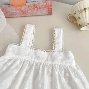 Vue à plat d'un haut débardeur blanc en coton pour fille avec broderie ajourée