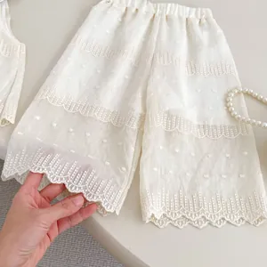 Detail of off-white lace shorts featuring intricate floral embroidery and elastic waistband