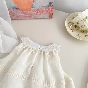 Close-up of white dotted swiss sleeveless top with delicate scalloped lace embroidery
