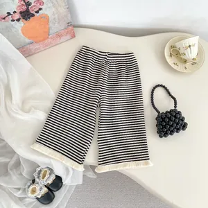 Dettaglio dei pantaloni a maglia a righe da bambina con orlo a nappa e vita elasticizzata