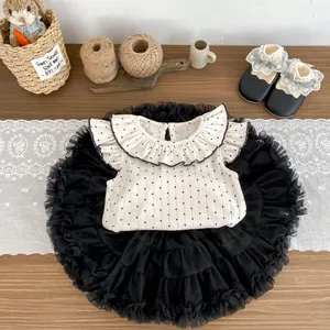 Detailansicht vom weißen Polka-Dot-Oberteil mit Rüschenkragen und schwarzem Tüllrock