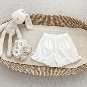 Detail of white cotton toddler shorts with ruffle hem and elastic waist in a basket
