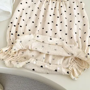 Détail d'un barboteuse bébé à motif cœurs, bords volantés et boutons-pression pratiques