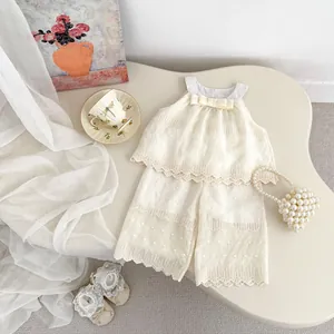 Flat lay of girl's summer set with lace ruffle top and wide-leg pants in creamy white