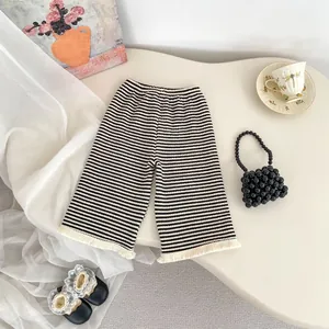 Dettaglio dei pantaloni a righe per bambina con frange di nappe bianche e vita elastica