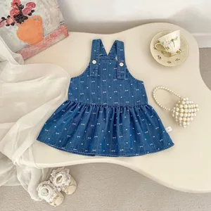 Detail of girls denim jumper dress with heart bow prints and white button closure