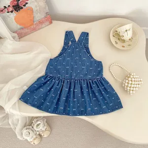 Detailed embroidery of white bows and hearts on a dark blue denim girl's jumper skirt