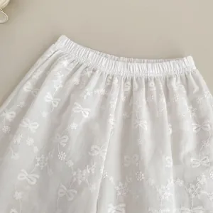 Détail du pantalon d'été en coton blanc avec broderie de fleurs et taille élastiquée