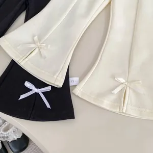Détail du pantalon évasé pour fille avec nœuds latéraux et fentes à l'ourlet