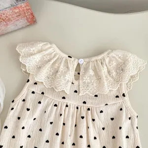 Détail du col en dentelle et motif de cœur sur le body sans manches pour bébé en crêpe