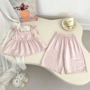 Detail eines rosa Baumwoll-Leinen Mädchen-Sommersets mit Schleifenträgern und Holzknöpfen