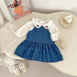 Detail of baby girl outfit showing cherry embroidery on collar and bow print denim dress