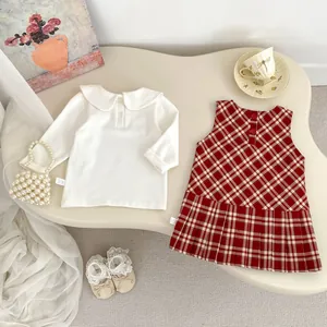 Dettagli completo vintage neonata con camicia bianca e abito a pieghe a quadri rossi
