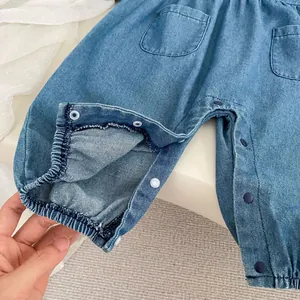 Detail of snap button closures and elastic cuffs on a light blue denim baby romper