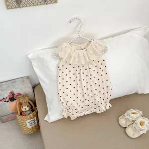 Gros plan d'une barboteuse bébé avec col en dentelle et imprimés cœurs sur coton crème
