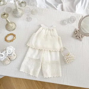 Detailed view of girls' white lace ruffled vest and pants set with dot embroidery