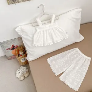 Détail de l'ensemble bébé blanc en coton avec broderie nœud et finitions dentelle