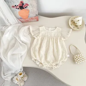 Detail of floral embroidery and mesh flutter sleeves on cream baby bodysuit