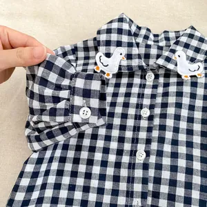 Close-up of black and white gingham shirt with cute white duck embroidery on collar