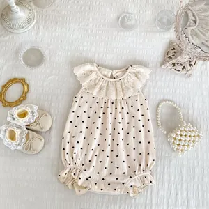 Détail d'une barboteuse bébé avec imprimé cœur, col en dentelle et boutons-pression