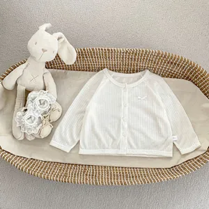 Détail d'un gilet blanc pour bébé en tricot côtelé avec petit nœud et boutons