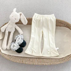 Détail du pantalon évasé crème pour bébés avec nœud décoratif dans un couffin