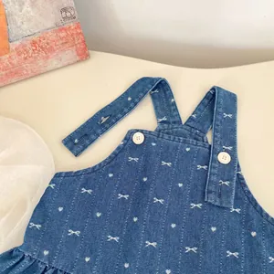 Navy denim baby girl suspender dress featuring white bow patterns and button details