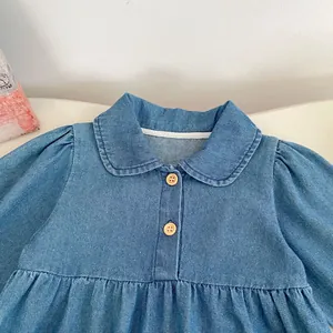 Detail of baby denim romper featuring Peter Pan collar and rustic wooden buttons
