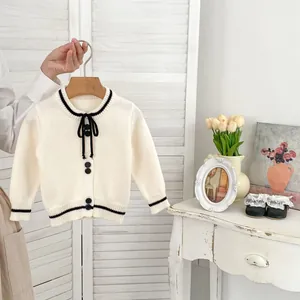 Detail of cream girls' knit cardigan with black contrast trim and chic bow tie