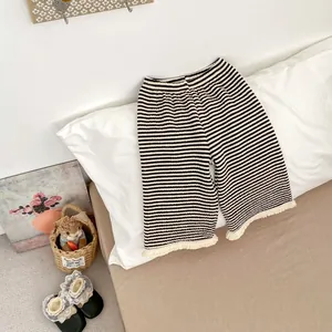 Dettaglio di pantaloni a righe per neonati con frange e scarpine di pizzo nero abbinate
