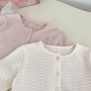 Dettaglio di cardigan in maglia per neonati con scollo rotondo e bottoni monopetto