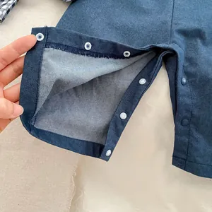 Detailed close-up of crotch snap fasteners on navy denim baby boy overall bodysuit