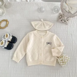 Flachliegende Baby-Strickjacke mit Rautenmuster und süßer schwarzer Schleifenstickerei