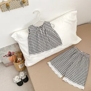 Detail of baby girl's black and white plaid set featuring delicate white lace trim on hem