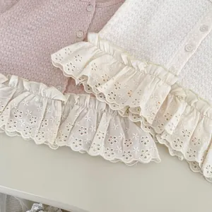Dettaglio del cardigan da bambina con bordo in pizzo delicato e trama in maglia