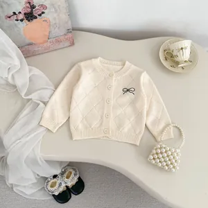 Detail der Baby-Strickjacke mit Rautenmuster und eleganter schwarzer Schleifenstickerei