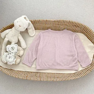 Detailansicht der rosa gerippten Babyjacke mit Plüschhase und Spitzen-Babyschuhen