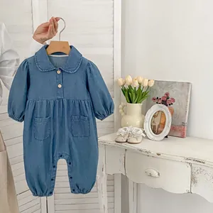 Detail of baby denim romper featuring wooden buttons and Peter Pan collar on a wooden hanger