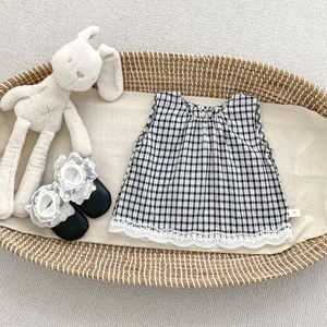Detail of baby girl plaid sleeveless top with ruffled collar and white lace trim