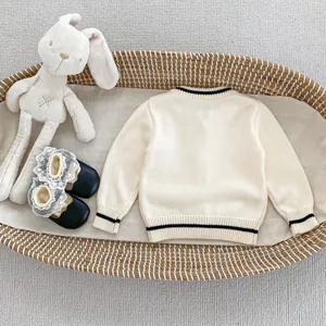 Detailed knit texture of girl's cream cardigan with black stripes and matching accessories