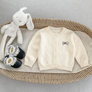 Nahaufnahme der Strickjacke mit Rautenmuster und Schleifenstickerei neben einem Hasen