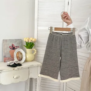 Dettaglio dei pantaloni a gamba larga a righe da bambina con frange bianche