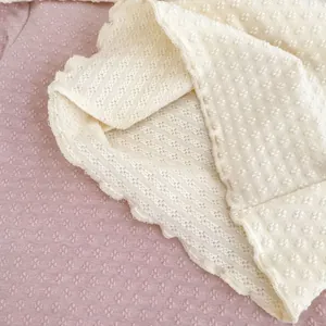 Nahaufnahme von Baby-Oberteil mit Wellensaum und punktierter Textur in Beigeweiß