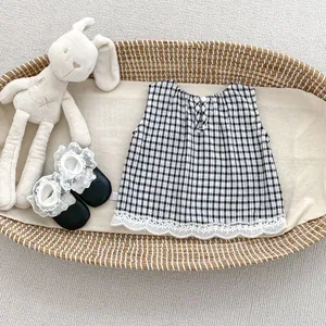 Detail of baby summer outfit featuring plaid sleeveless top with lace trim and bow shoes