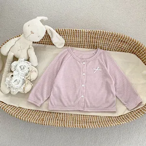 Détail du cardigan de protection solaire rose clair avec boutons et nœud