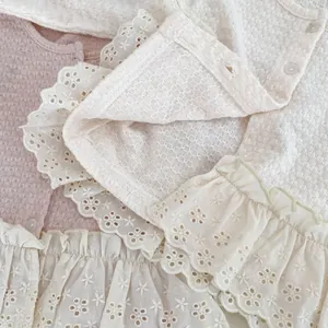 Dettaglio del cardigan neonata con trama a nido d'ape e ricamo floreale delicato