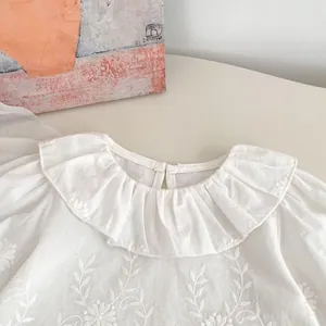 Close-up of girls cotton shirt featuring ruffle collar and floral embroidery details