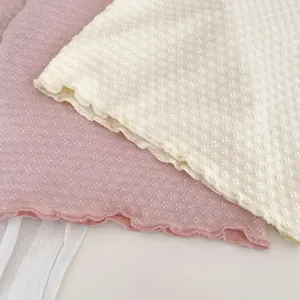 Nahaufnahme von Baby-Strickoberteilen mit Jacquard-Textur und feinen Wellensaum-Details