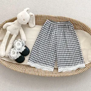 Detail of girls' black and white plaid wide-leg trousers with elegant white lace hem