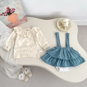 Detailed flat lay of baby bow print top and blue corduroy suspender skirt outfit